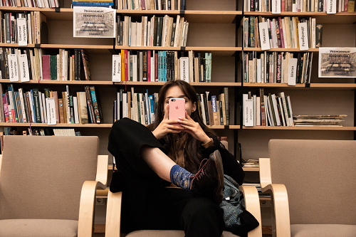 woman sitting in a library using an iphone