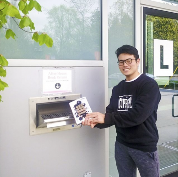 A Langara student returns a book using the Library's outdoor book drop.