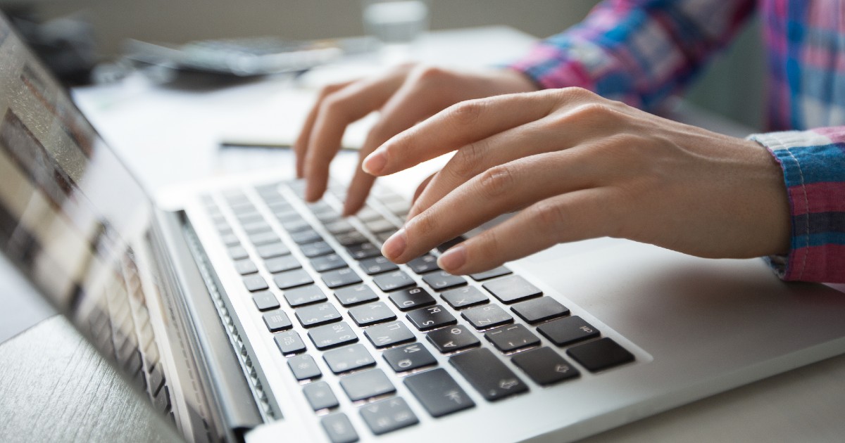Photograph of a person's hands above a laptop keyboard.