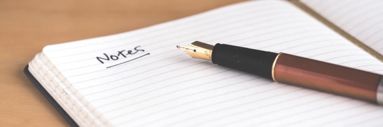 A pen on an open notebook with the word "Notes" written on the page.